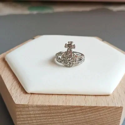 silver ring with an orb and cross crest on a wooden display block