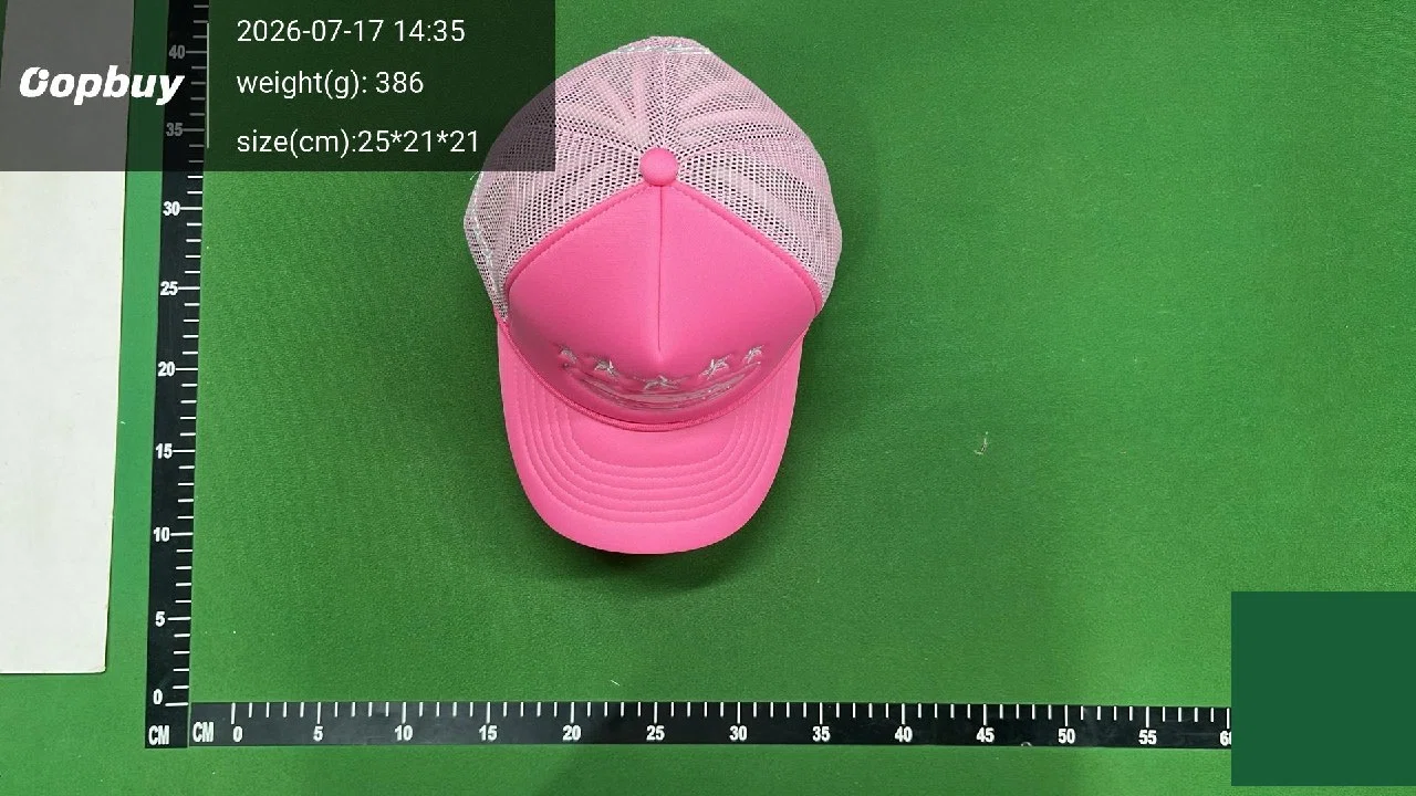 full warehouse inspection frame of a pink mesh trucker cap on a green centimetre mat with timestamp, weight and size overlay in the corner